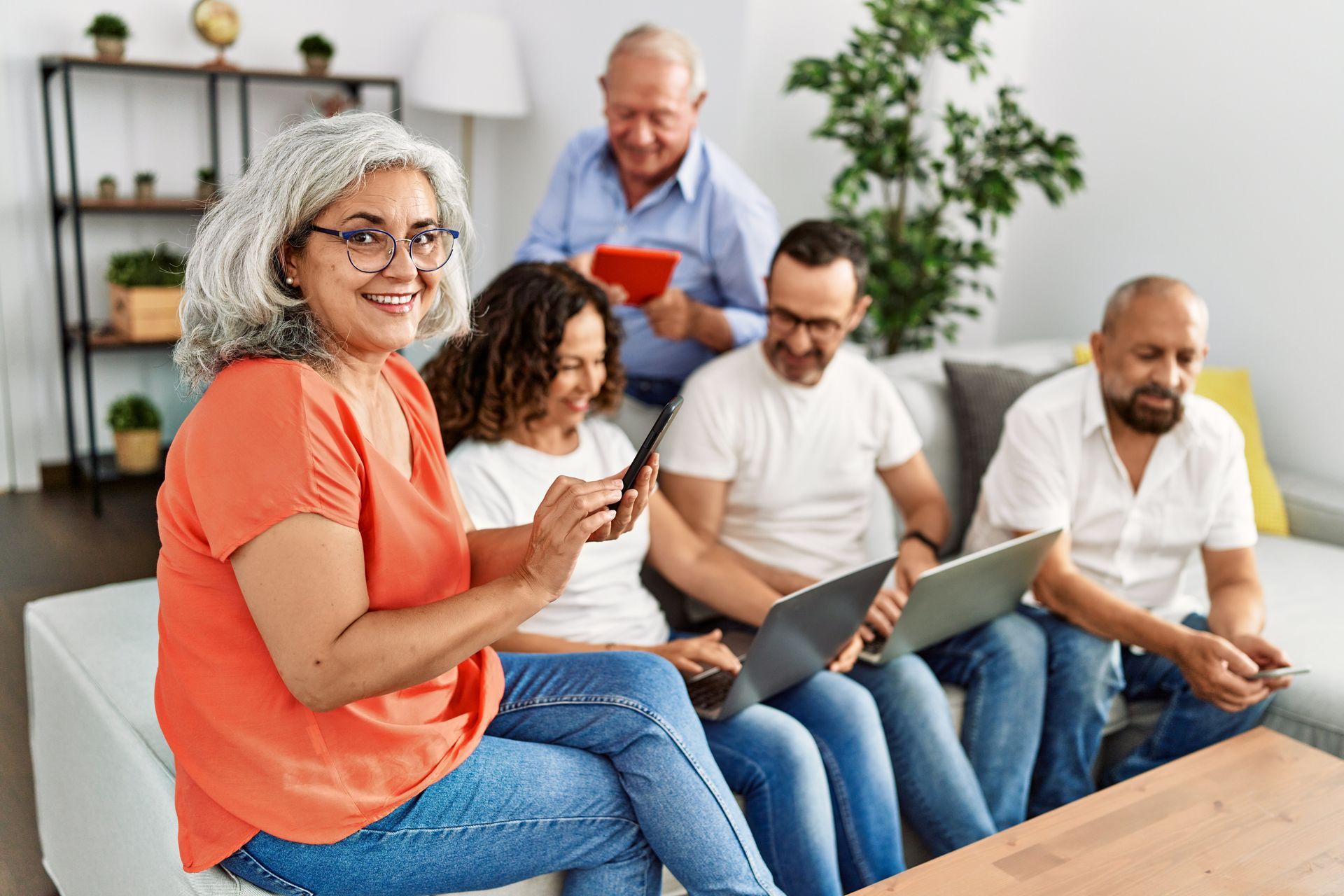 A group of people are sitting on a couch using laptops and tablets.