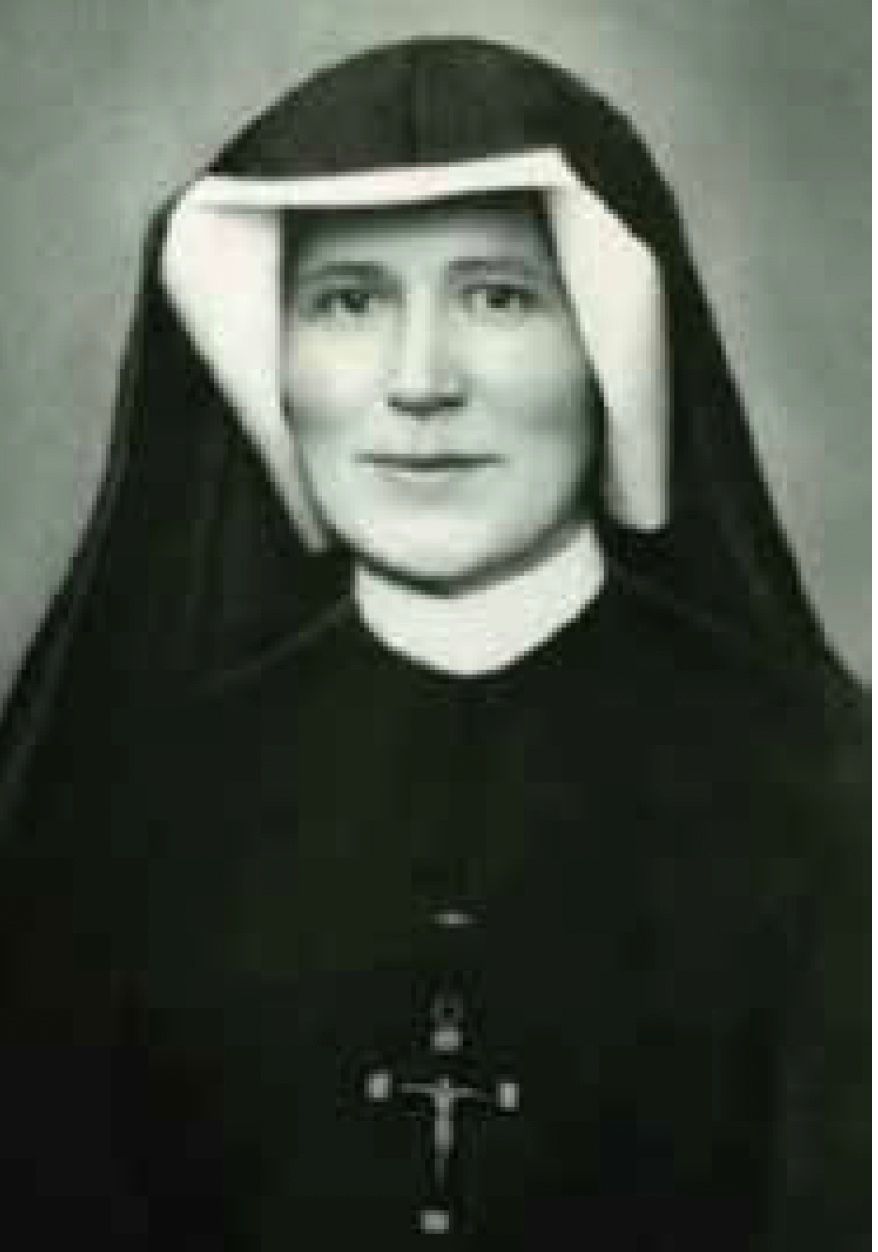 A black and white photo of a nun with a cross on her chest.