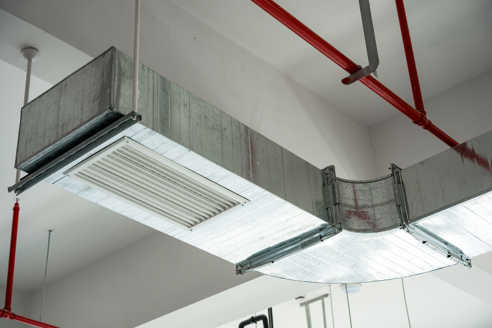 Indoor ceiling-mounted metal ventilation ducts with fire protection piping systems.