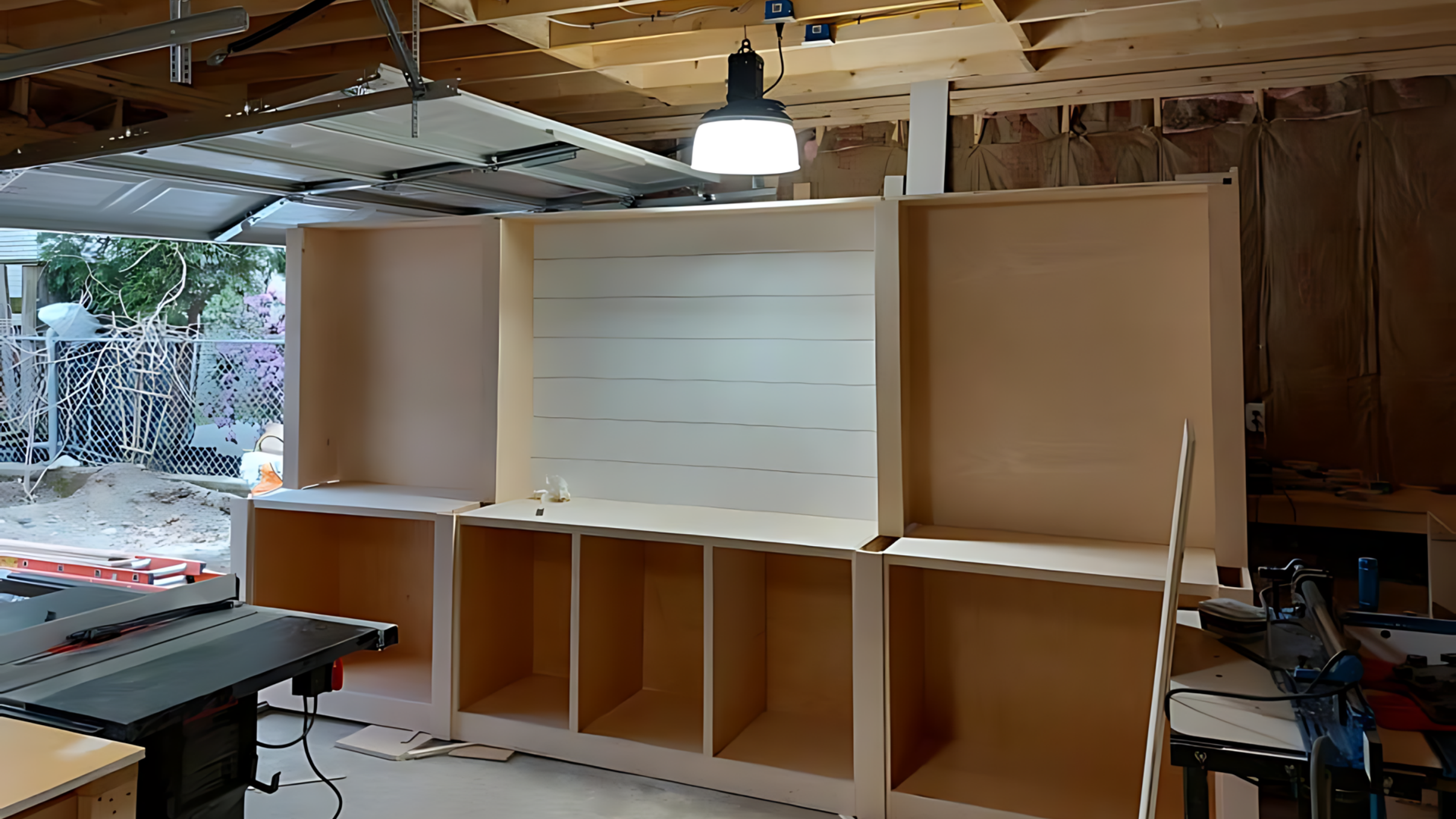 Built-in cabinet under construction in a workshop, with white center doors and open lower shelves.