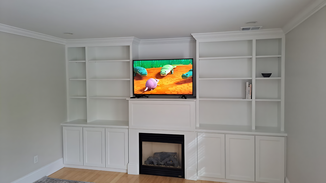 Bright living room with white built-in shelves, a fireplace, and a TV showing a colorful scene.