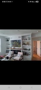 Bright living room with white built-in shelves, fireplace, and two chairs by a large window.