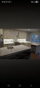 Modern kitchen with white cabinets, large island, and stainless steel appliances at night
