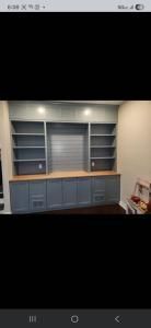 Built-in blue-gray cabinets with open shelving and wood countertop against a beige wall.