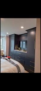 Modern bedroom with dark built-in cabinets, recessed ceiling lights, and a partially visible bed