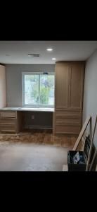 Bright room with a desk, large window, wood floor, and a leaning framed mirror on the right.
