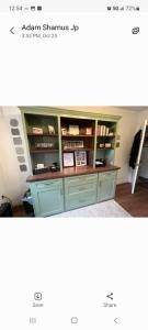 Green wooden display cabinet with shelves and drawers in a bright room