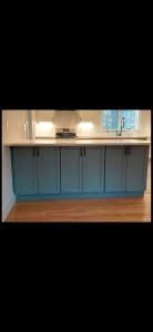 Blue kitchen island with white countertop, sink, and faucet in a bright home kitchen