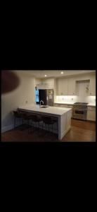 Modern kitchen with white cabinets, large island, pendant lights, and hardwood floors