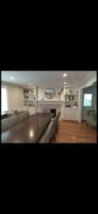 Bright dining room and kitchen with wooden table, white cabinets, pendant lights, and hardwood floor