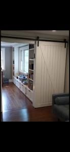 Sliding barn door in a hallway opening into a bright kitchen, with hardwood floors and a couch edge.