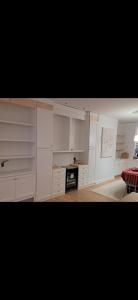 Bright living room with white built-in shelves, a fireplace, and a red sofa near a window.