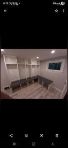 Bright walk-in closet with white shelves, hanging rods, and an L-shaped dark countertop
