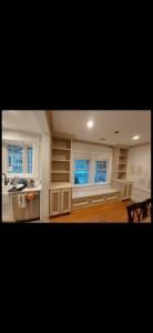 Built-in white shelving and cabinets around a window in a bright room with hardwood floors