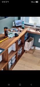 Wooden desk with a monitor, keyboard, water bottle, mugs, and shelves in a bright room