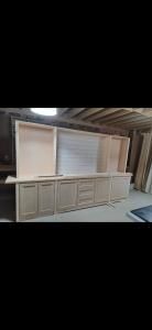 Large beige built-in cabinet with shelves and drawers in a workshop or garage setting