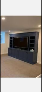 Built-in navy media cabinet with a large TV in a beige living room