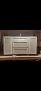 White wooden cabinet with drawers and side doors on a shelf in a display room