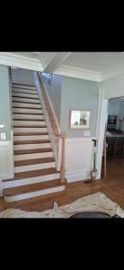 Interior staircase with white risers, gray railings, and hardwood floors in a bright home hallway
