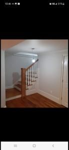 Empty room with hardwood floors and a staircase railing against white walls.