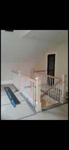 Interior stair landing with white railing, black handrail, and a blue step ladder nearby