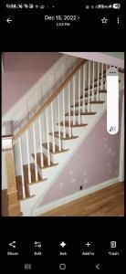 Wooden staircase with white railing and pink walls in a home interior.