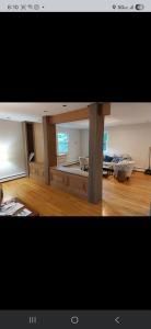 Modern open-plan room with wood floors, glass partitions, and a desk by the windows