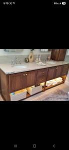 Kitchen counter with wooden cabinets, sink, dish rack, and under-cabinet storage bins