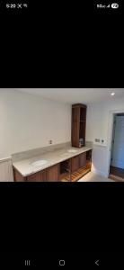 Empty room with white walls, built-in countertop cabinets, and a tall wooden storage cabinet by a door.