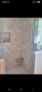 Tiled shower stall with a built-in corner shelf and a window beside a white radiator.