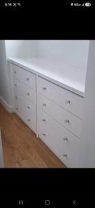 White built-in drawers with a countertop along a wall on a wood floor.
