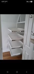 White pull-out pantry shelves inside an open closet with a hardwood floor.