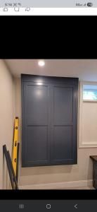 Dark blue built-in cabinets under a ceiling light, with a yellow ladder leaning nearby.