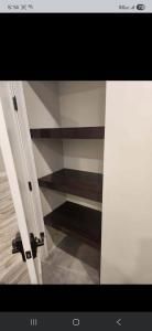Open pantry closet with dark shelves and white walls inside a kitchen hallway.