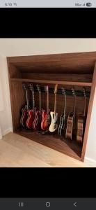 Guitar storage alcove with several electric guitars lined up on wooden shelves.