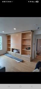 Bright living room with built-in wooden shelves, a fireplace, and a long low bench by a window.