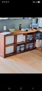 Wooden kitchen counter with shelves and storage bins in a bright room.