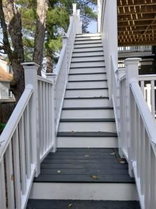 Steep white outdoor staircase with railings leading up beside a house