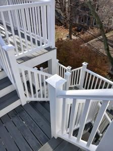 White deck stairs with railings descending to a wooded yard.