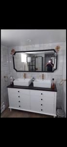 Modern bathroom vanity with double sink, large mirror, and wall sconces in a gray room