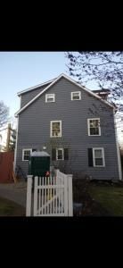 Gray two-story house with white trim and a white gate in front yard