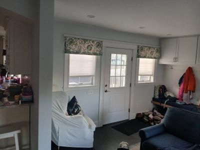 Small living room with white door, windows, navy sofa, and a white chair in the foreground.