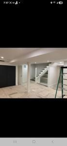 Empty modern room with white staircase, tiled floor, and black garage-style door