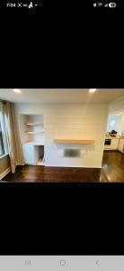 Empty white room with built-in shelves, a floating desk, and dark hardwood floors.