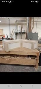 White curved cabinet or countertop in a workshop, with tools and a wooden workbench in the background