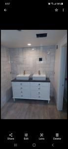 Modern bathroom vanity with double sinks, large mirror, and tiled walls in a clean neutral space
