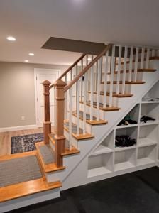 Wood staircase with white railing and built-in storage shelves in a carpeted hallway