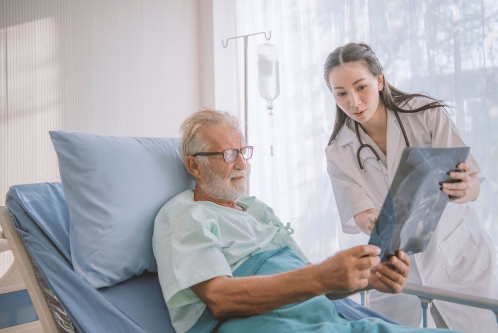 Doctor Reviewing X-ray With Patient in Hospital Bed — HealthHub Taree in Taree, NSW