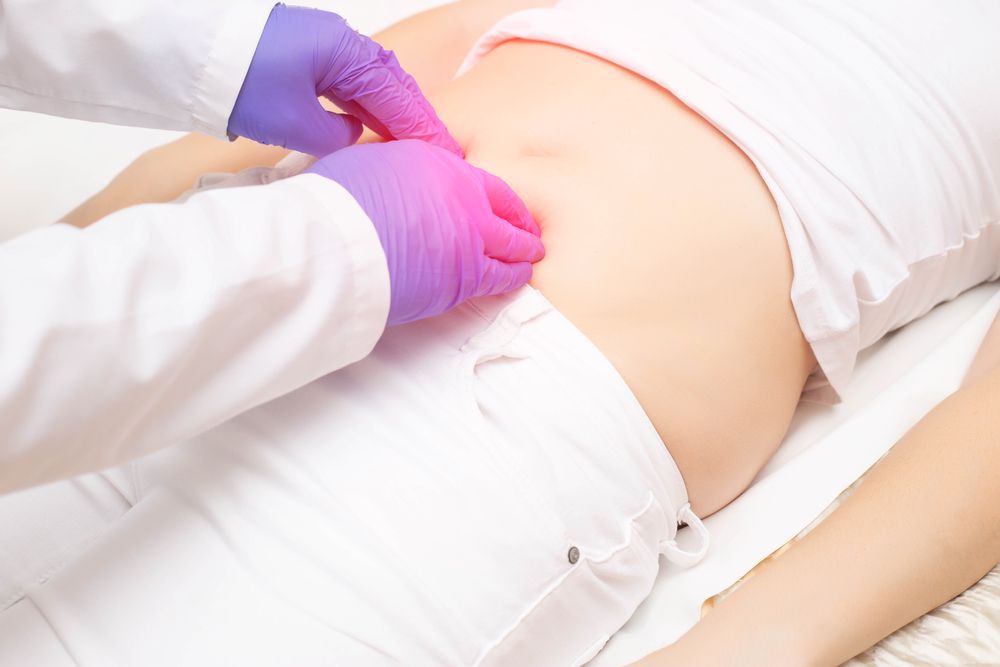 Gloved Hands Examining a Person’s Abdomen During a Medical Procedure — HealthHub Taree in Taree, NSW