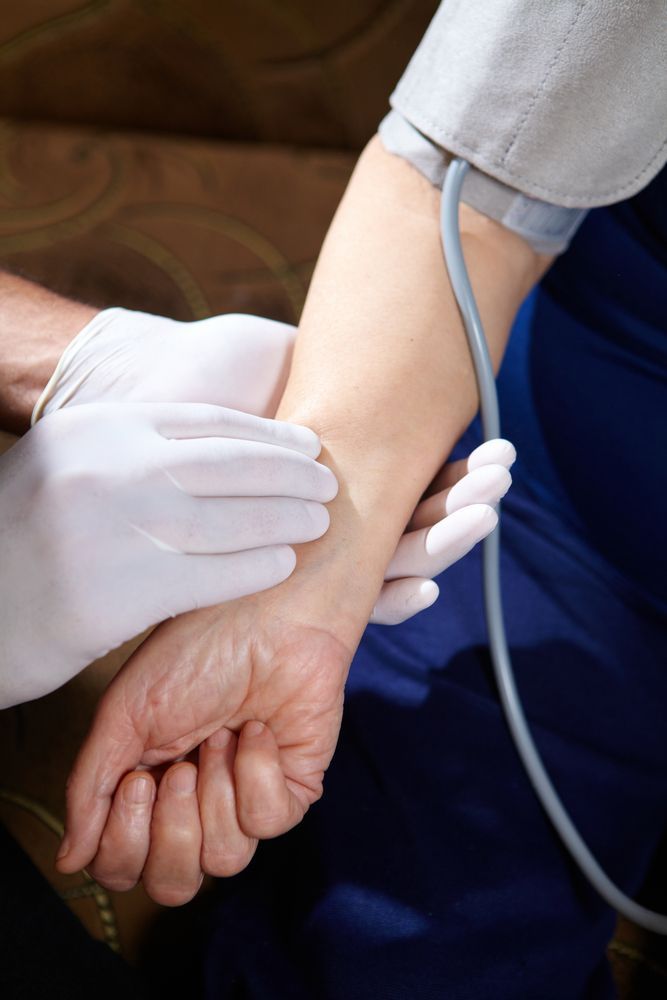 Gloved Hands Taking a Patient’s Wrist Blood Pressure in a Clinical Setting — HealthHub Taree in Taree, NSW